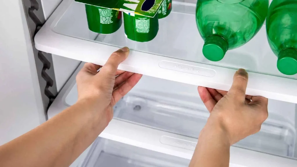 Pessoa utilizando o sistema de regulagem das prateleiras Altura Flex dentro da Geladeira Consul CRM39AK 340L