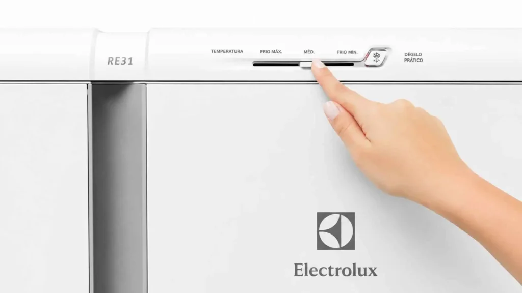 Mão de uma pessoa ajustando o painel de controle externo de temperatura da geladeira Electrolux 240L RE31