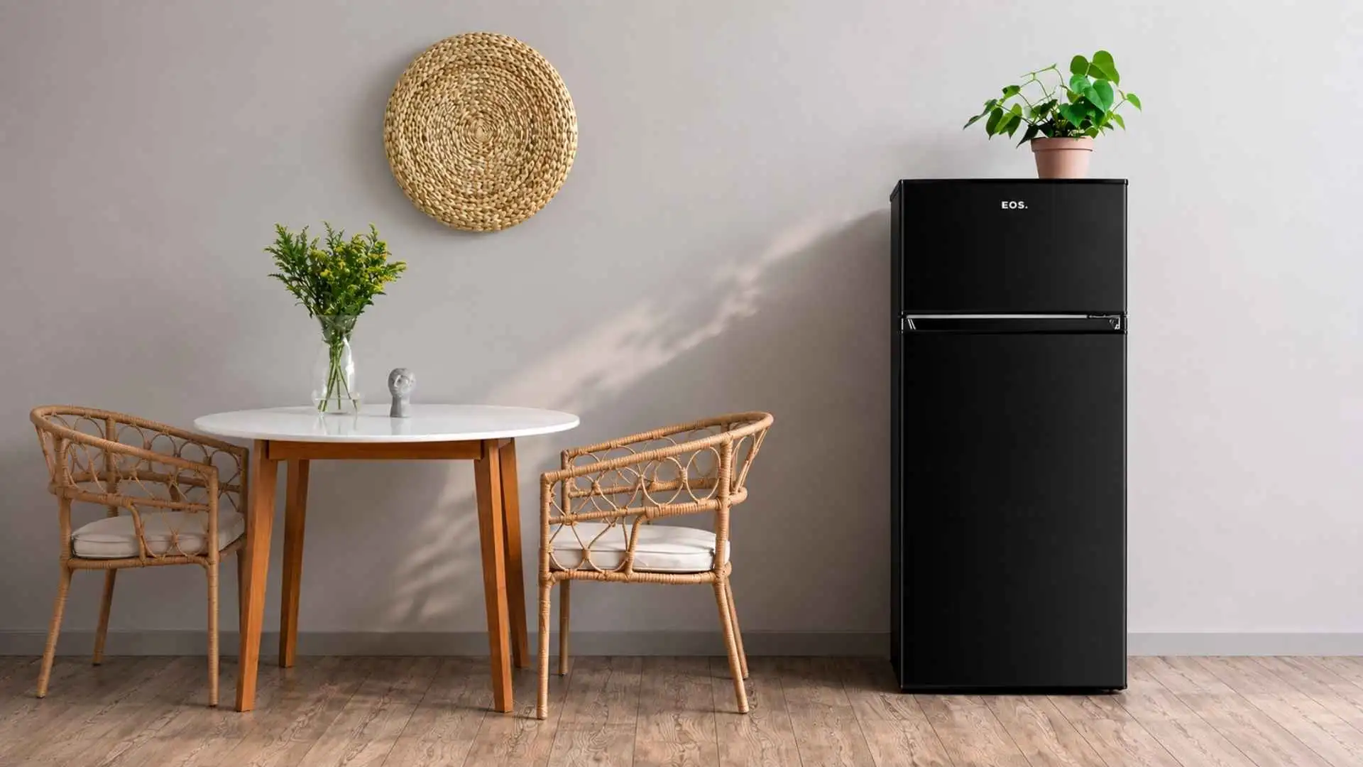 Visão frontal da geladeira EOS ERV250DP 230L preta fechada em um ambiente de cozinha moderna ao lado de uma mesa de madeira