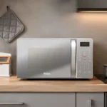 Micro-ondas Philco 20L Espelhado PMO23E instalado sobre a bancada de uma cozinha moderna